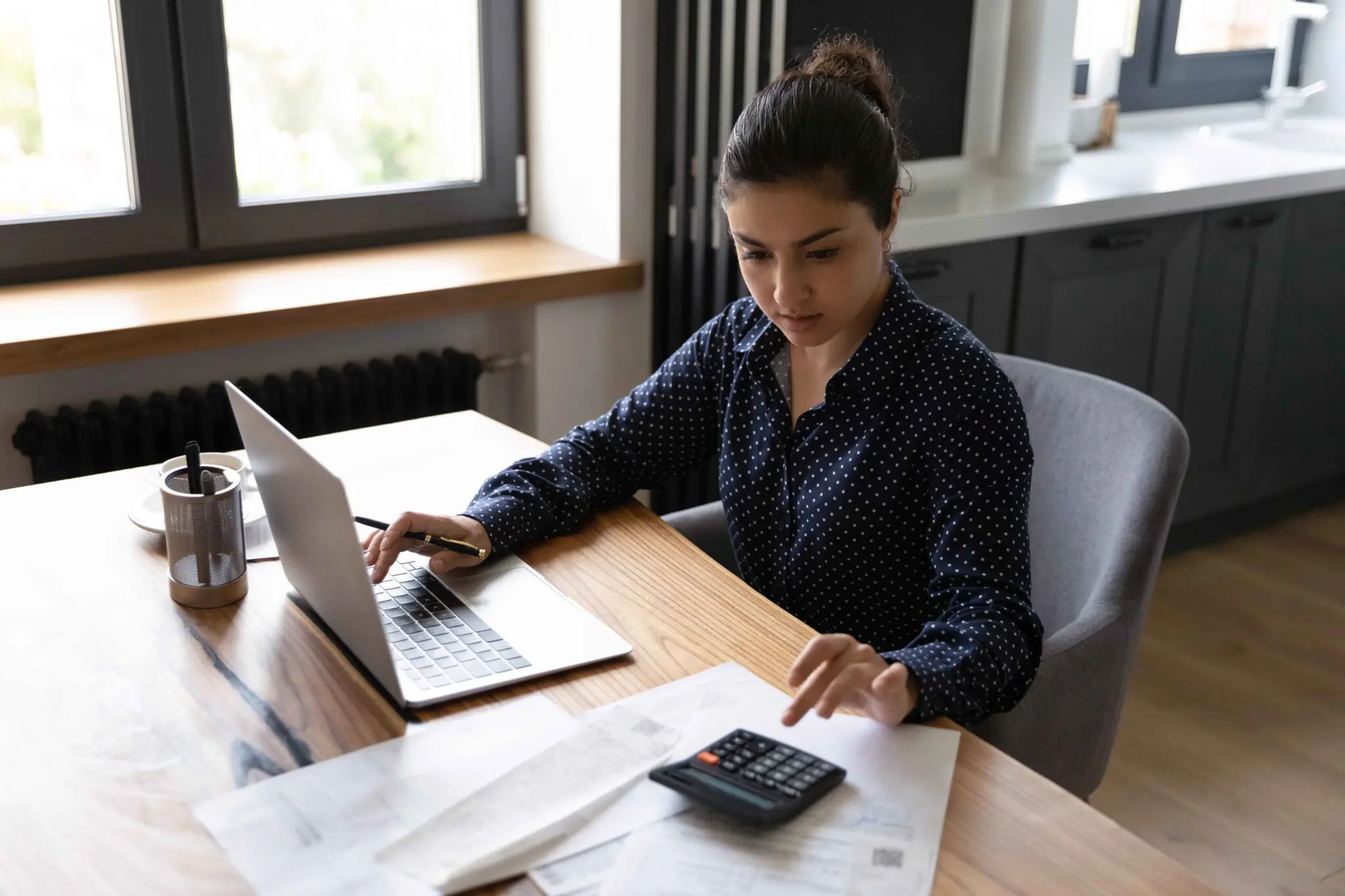 Woman working on laptop and calculator.