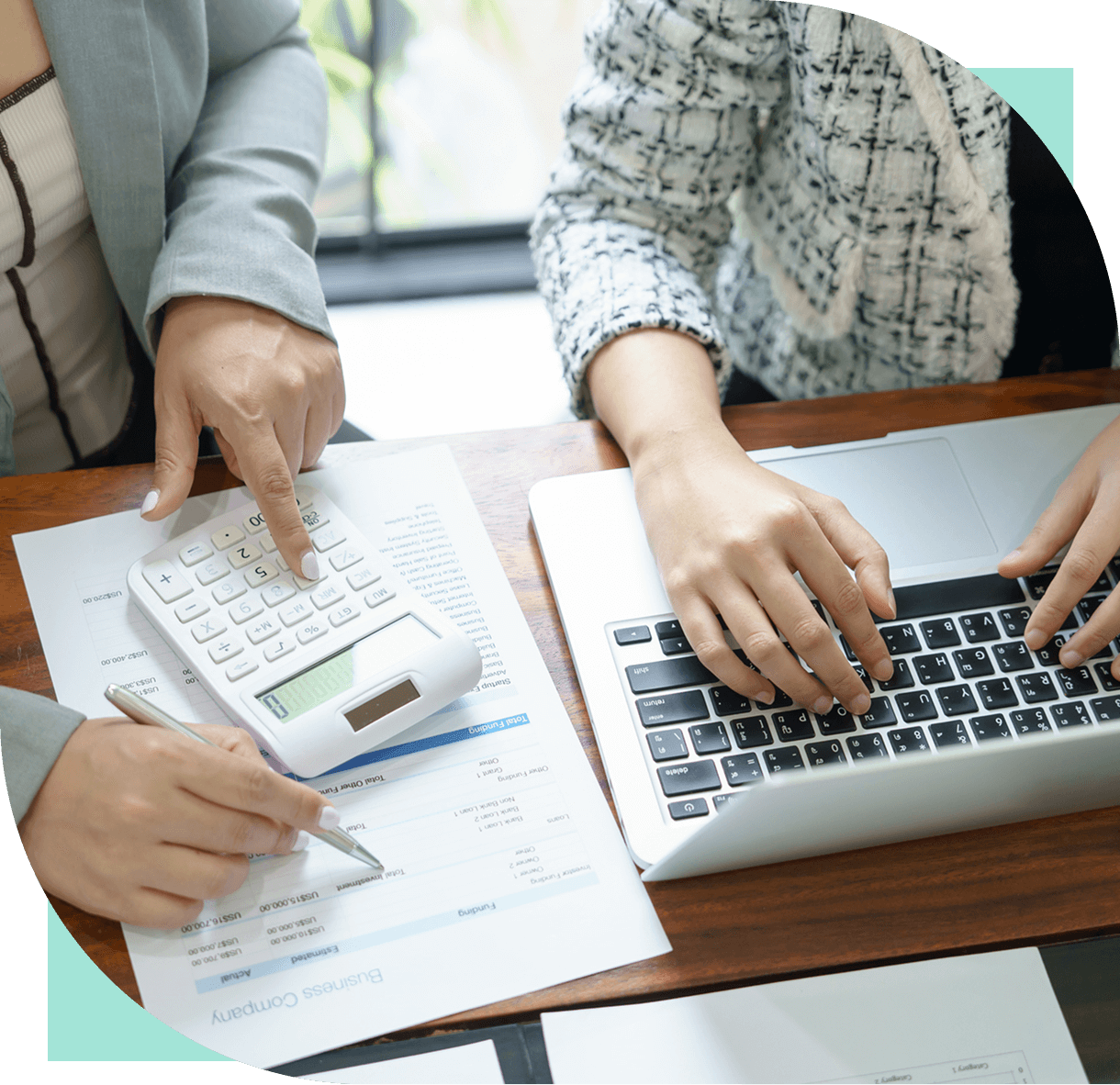 Hands using laptop and calculator on desk.